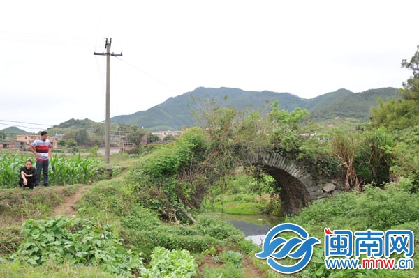 已廢棄的石拱橋，被野草覆蓋，下有溪流，村民稱此路